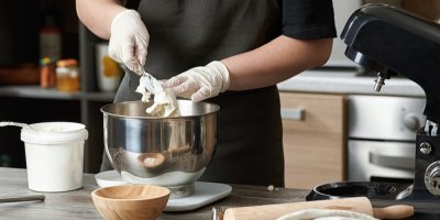 Člověk v kuchyni používá kuchyňský robot na přípravu těsta