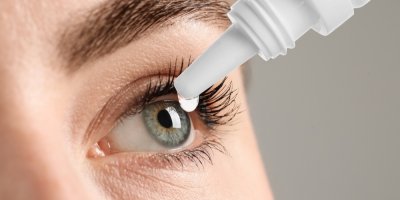 Žena si kape oční kapky do oka