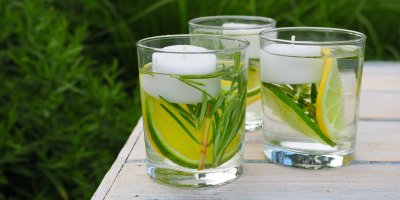 Tři sklenice, ve kterých jsou limetky, citrony, rozmarýn, olej a svíčky