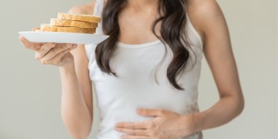 Žena drží v ruce talíř s chlebem a druhou rukou se drží za břicho