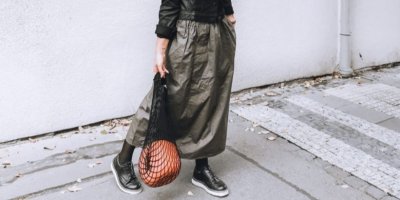 Žena na ulici drží v ruce síťovou tašku 