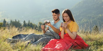 Muž a žena ve spacáku uprostřed louky