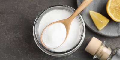 Jedlá soda ve sklenici se lžící, vedle citron a lahev