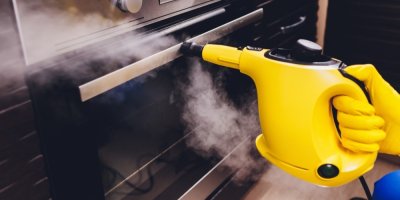 Člověk čistí troubu parním čističem