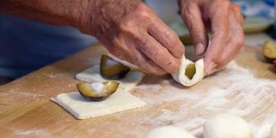 Starší žena připravuje švestkové knedlíky