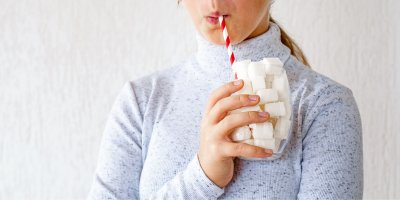 Žena pije kostkový cukr ve sklenici