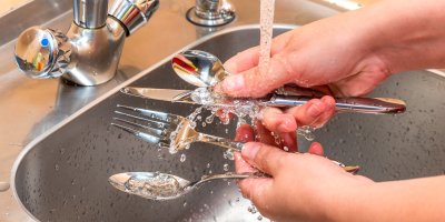 Mytí příborů pod vodou ve dřezu