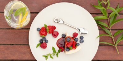 Tvarohový koláč s lesními plody a mátou se sklenicí ledové vody a citronem na dřevěném prkénku s citronovou verbenou