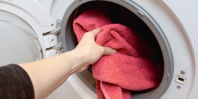 Žena dává do pračky červený ručník