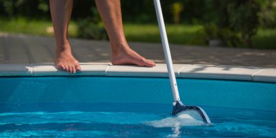 Člověk čistící vodu v bazéně síťkou