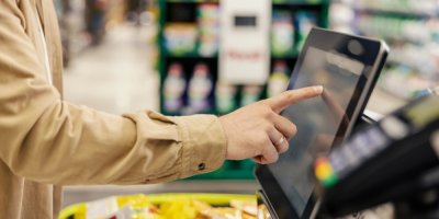 Člověk se dotýká displeje samoobslužné pokladny