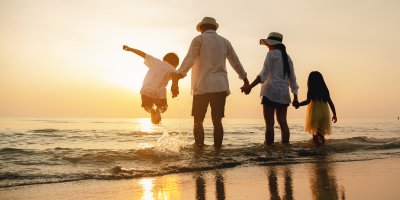 Rodiče s dcerou a synem se dívají na západ slunce na pláži