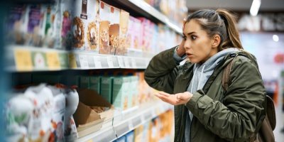 Žena v supermarketu stojí překvapeně u regálu