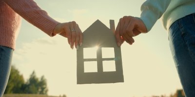 Muž a žena drží model rodinného domu z kartonu