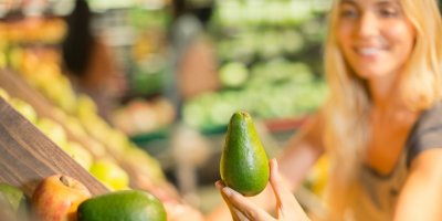 Žena drží avokádo v obchodě