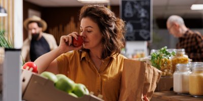 Žena čichá k jablku v obchodě