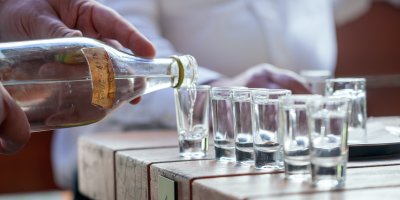 Muž rozlévá domácí slivovici do panáků