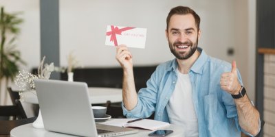 Muž se usmívá a v ruce drží dárkový poukaz