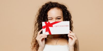 Žena drží před obličejem dárkový voucher