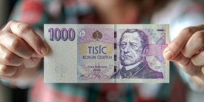 Člověk drží v rukou českou tisícikorunovou bankovku