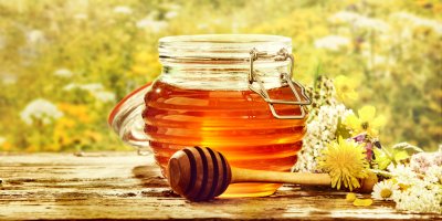 Med ve skleněné lahvi, okolo květiny