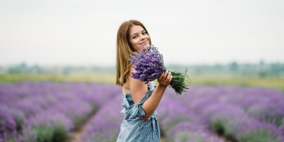 Žena v levandulovém poli drží kytici levandule