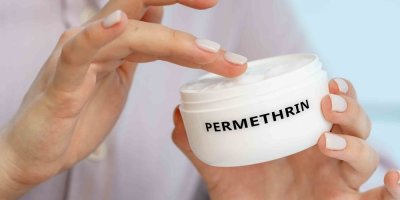 Žena drží v rukou krém s účinnou látkou permethrin