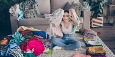 Mladá vystresovaná žena v pokoji plném oblečení 