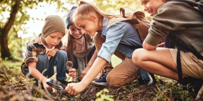Děti zkoumají něco lupou v lese