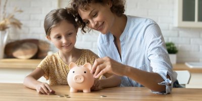 Dcera s matkou dávají peníze do prasátka