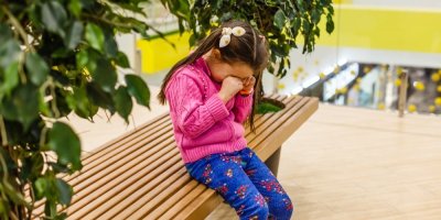 Plačící dívka na lavičce v obchodním centru