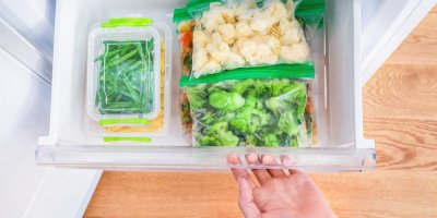 Žena otevírá mrazák s mraženou zeleninou