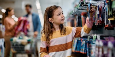 Dívka si prohlíží v obchodě psací potřeby.