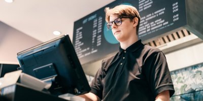 Mladý prodavač v černém tričku za pokladnou