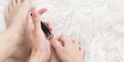 Žena si stříhá nehty na nohou