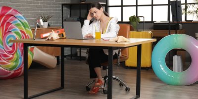 Mladá žena sedí zklamaná v kanceláři v době letních dovolených