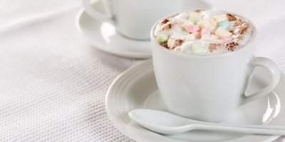 Kávový nápoj v bílém hrníčku s barevnou ozdobou