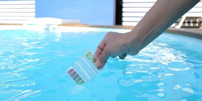 Ruka s testerem pH vody v bazéně