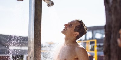Muž si dává sprchu u veřejného bazénu.