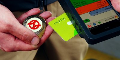 Ruka revizora s terminálem a odznakem v ruce