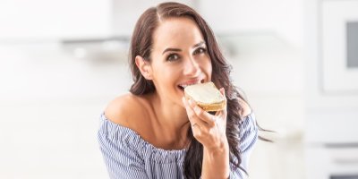 Žena jí namazaný krajíc chleba