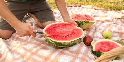 Muž krájí meloun na pikniku