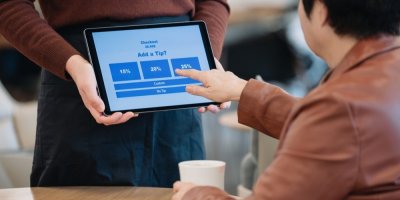 Zákazník volí výši spropitného na tabletu, který drží zaměstnanec kavárny