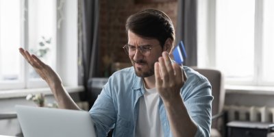 Muž s nechápavým výrazem sedí u notebooku a drží v ruce platební kartu