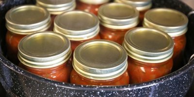 Zavařovací sklenice naplněné omáčkou v hrnci