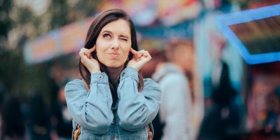 Žena si zacpává uši a tváří se podrážděně.