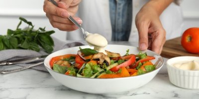 Žena si přidává do salátu majonézu