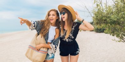 Dvě mladé ženy na pláži ve volném plážovém oblečení.