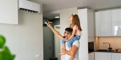 Otec a dcera v kuchyni, otec zapíná ovladačem klimatizaci