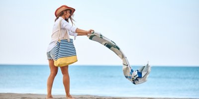 Žena dává osušku na písek u moře